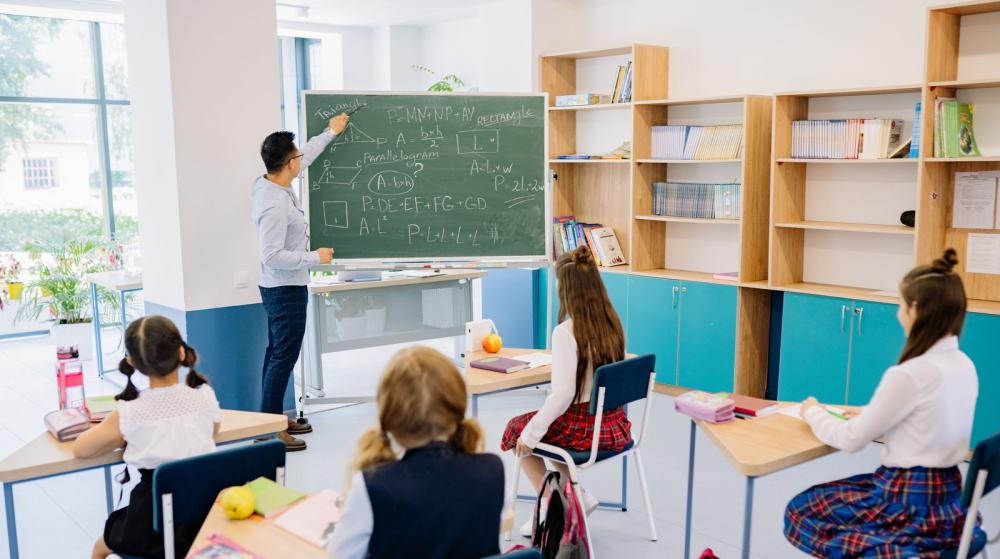 Dzieci w ławkach i nauczyciel podczas lekcji w klasie — zdjęcie ilustracyjne