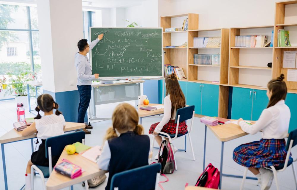 Dzieci w ławkach i nauczyciel podczas lekcji w klasie — zdjęcie ilustracyjne