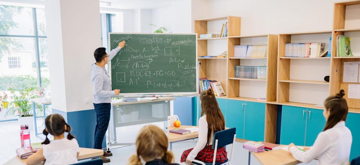 Dzieci w ławkach i nauczyciel podczas lekcji w klasie — zdjęcie ilustracyjne