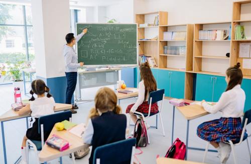 Dzieci w ławkach i nauczyciel podczas lekcji w klasie — zdjęcie ilustracyjne